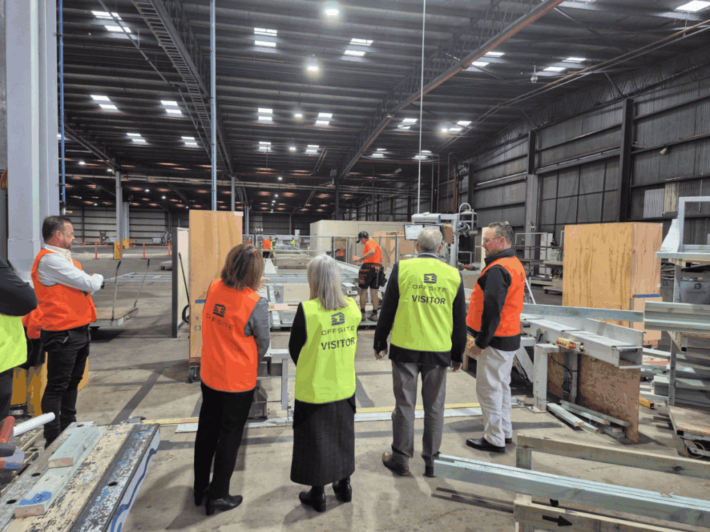 Sandra Brewer, David Bolt and the Offsite Team in orange vests standing in a warehouse.